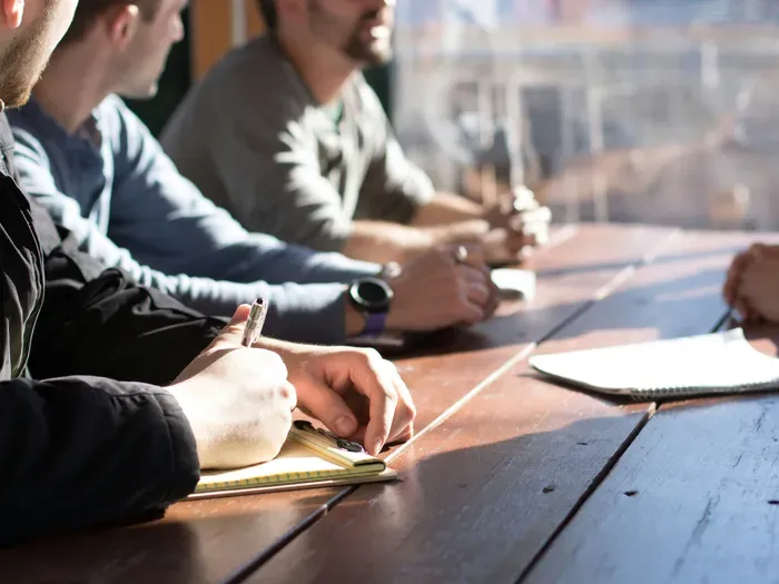 Group of people taking notes at a table, showing community meetings where residents find city services